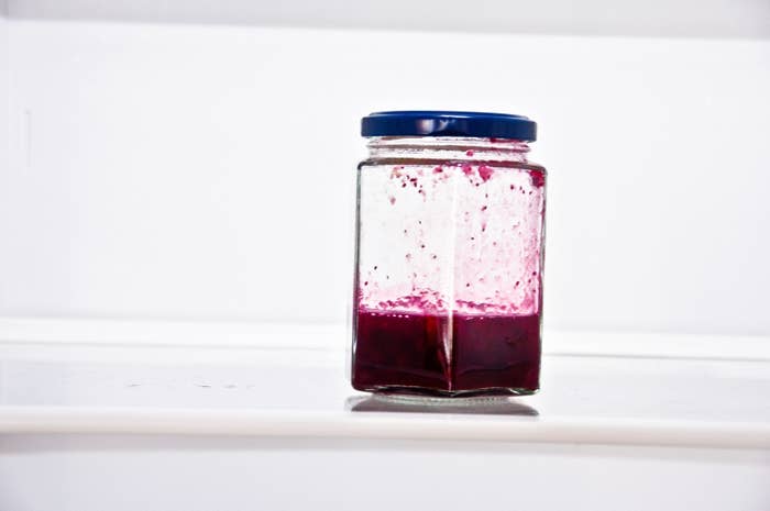 A quarter-full jar of jam on an otherwise refrigerator shelf