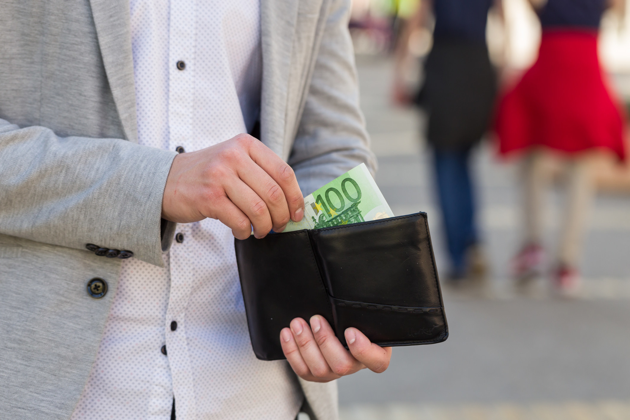 hands pulling out 100 euros from a wallet