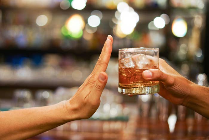 a person's hand up stopping from being handed a drink