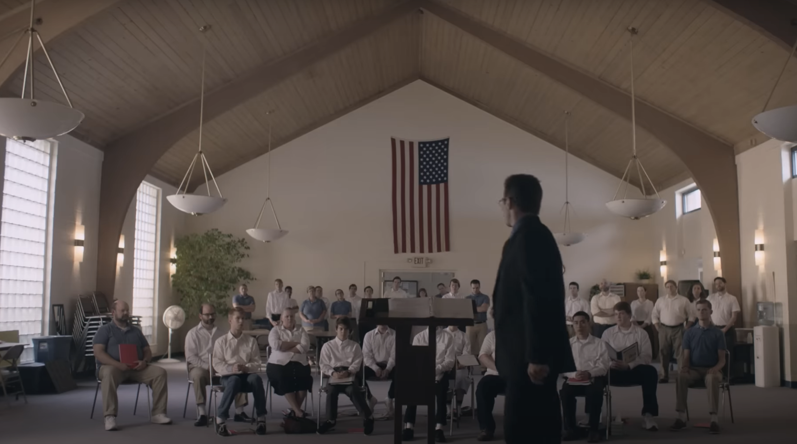 man approaching podium in front of group of teen boys