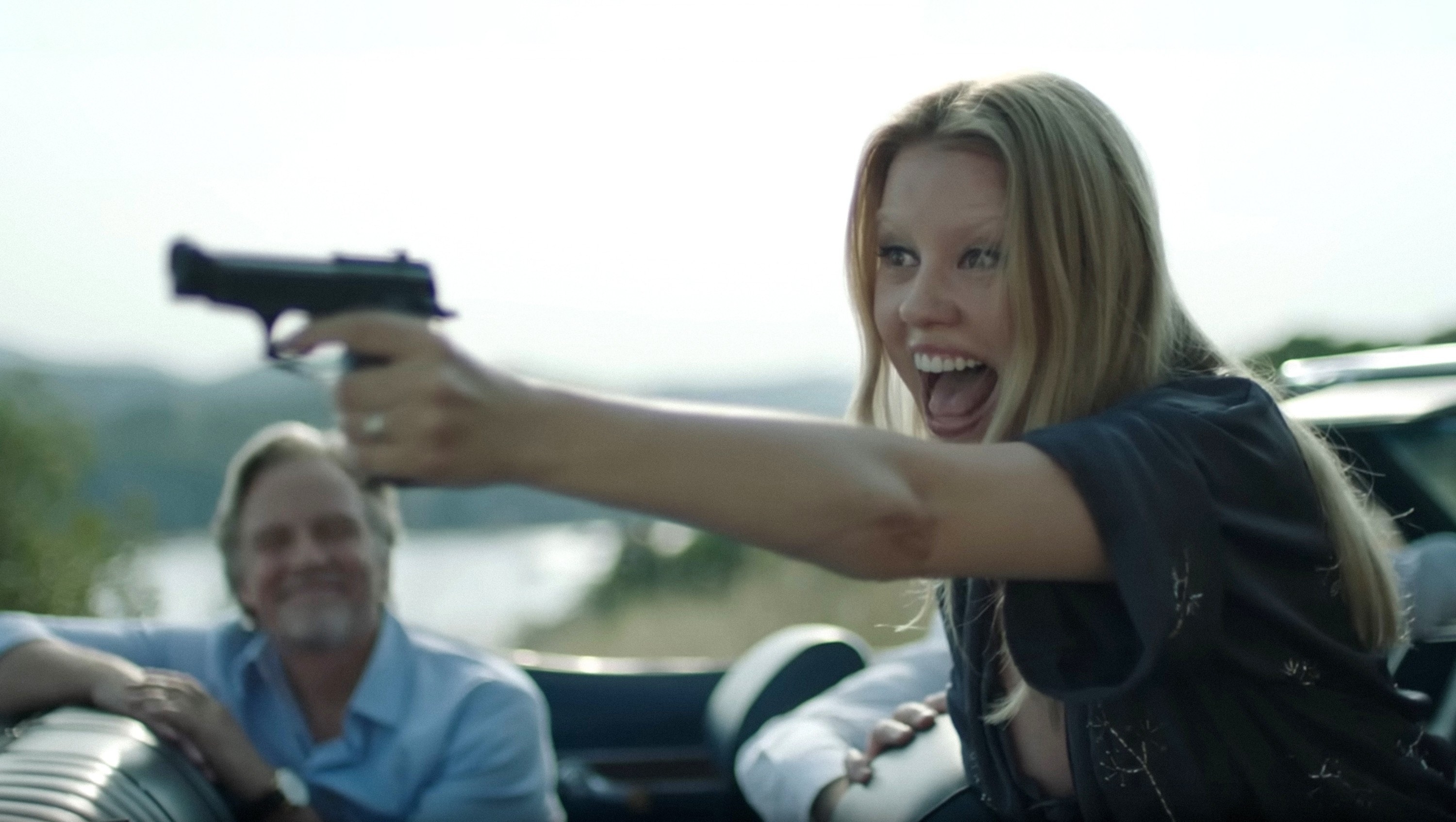 Mia holding a gun and smiling in a scene
