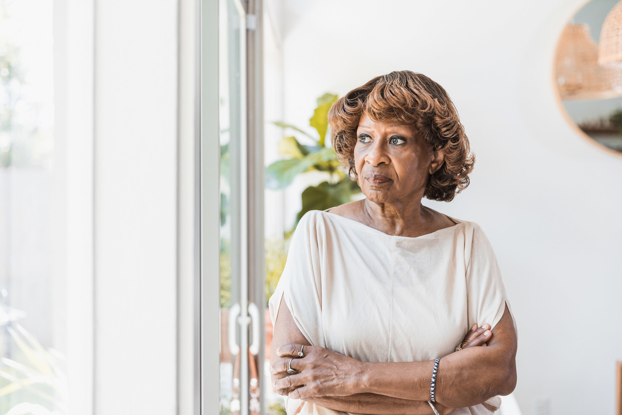 woman with her arms crossed looking out the window