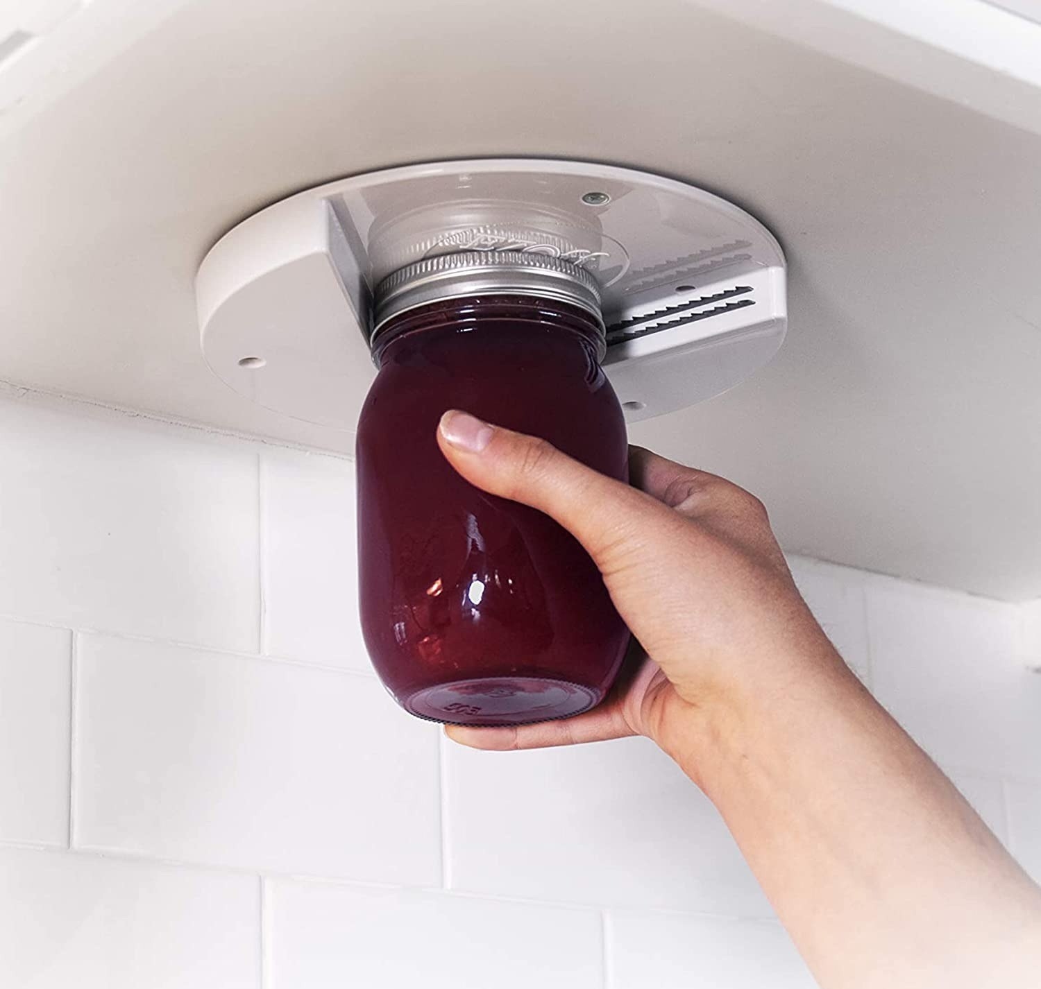 hand using under-the-cabinet jar opener to open jar