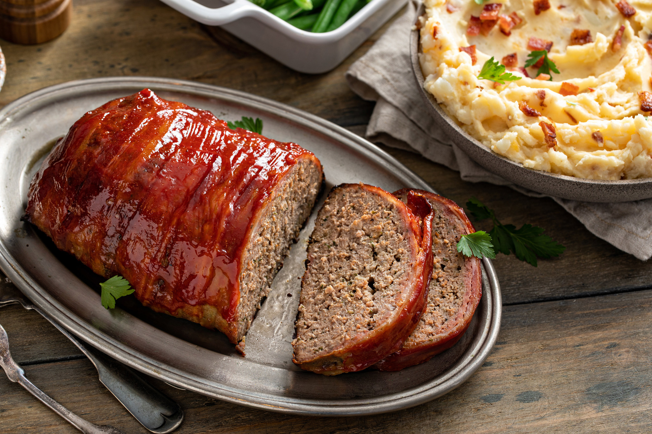 Bacon-wrapped meatloaf sliced on a serving plate for dinner
