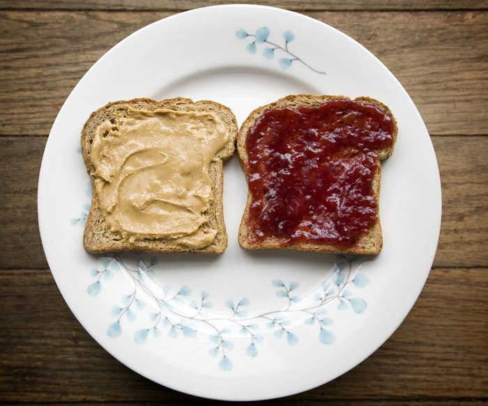 Two pieces of bread, one with peanut butter other with jelly