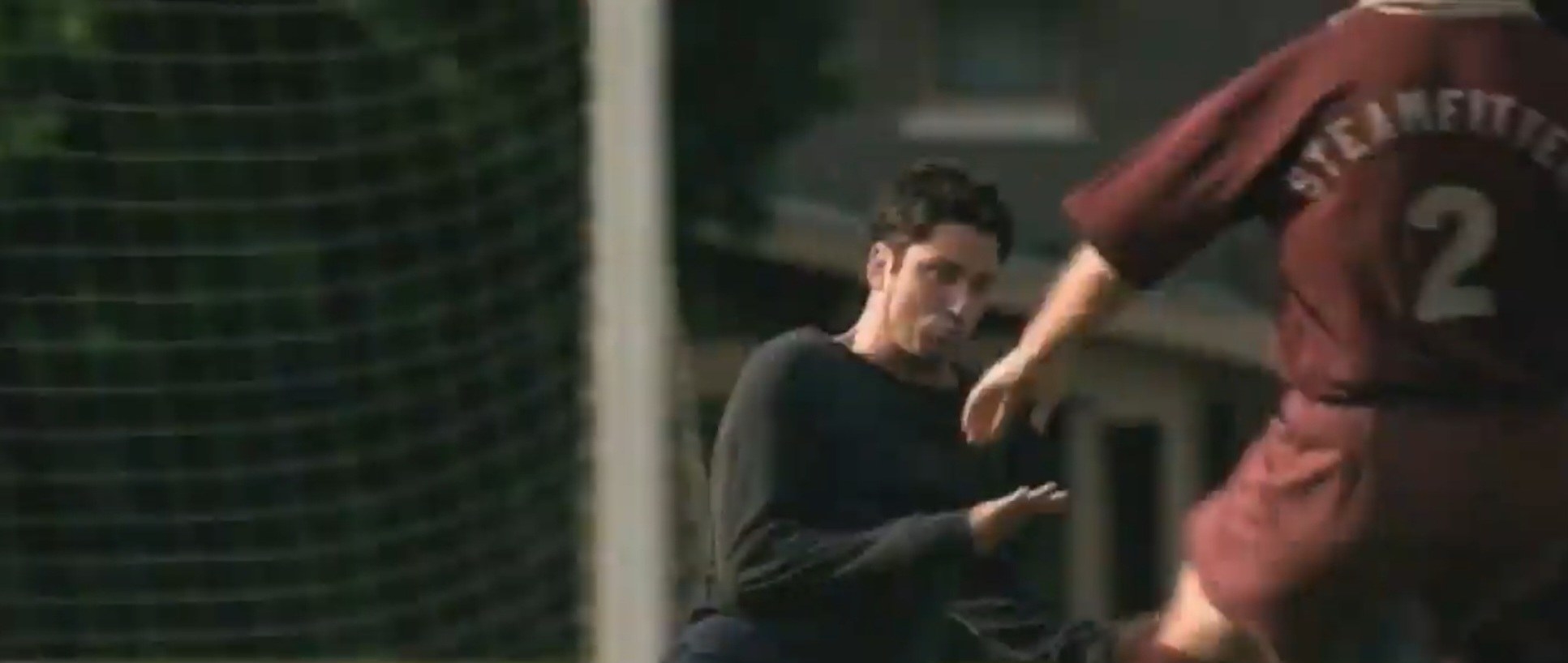 A goalie in a black sweater attempts to stop a kick during a soccer game