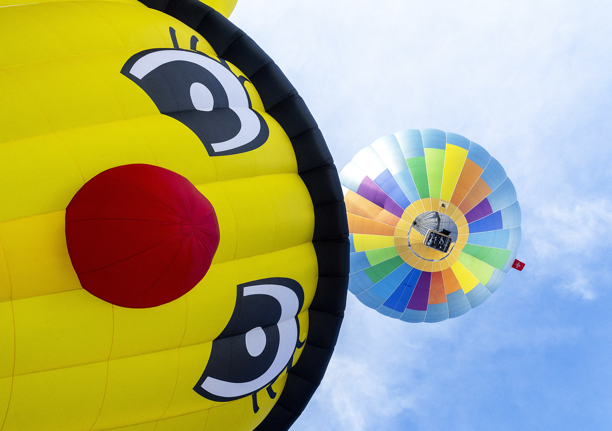 a gigantic bright yellow hot air balloon that looks like a red-nosed cartoon caterpillar