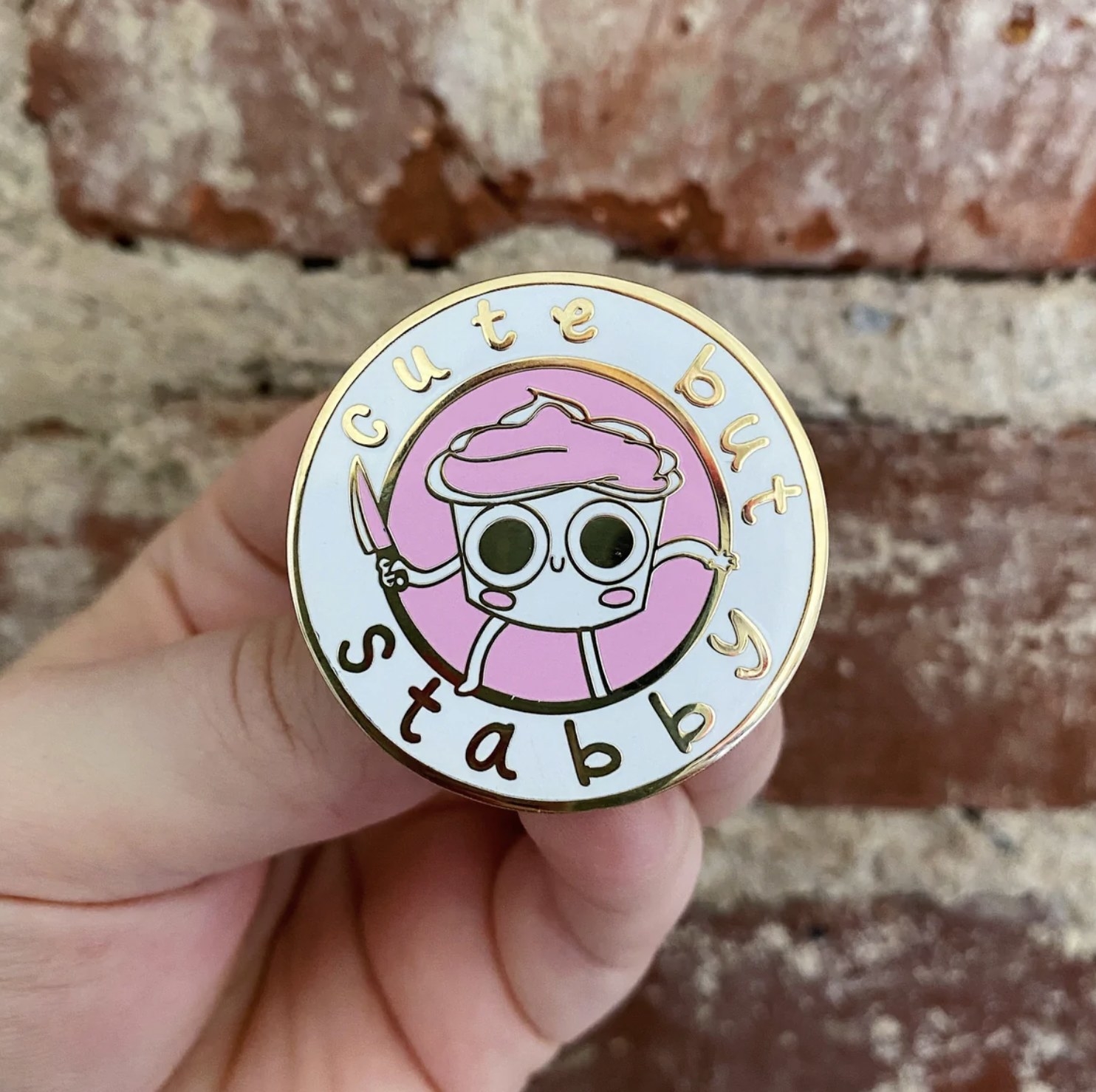 the pin that has as an animated cupcake holding a knife that says cute but stabby
