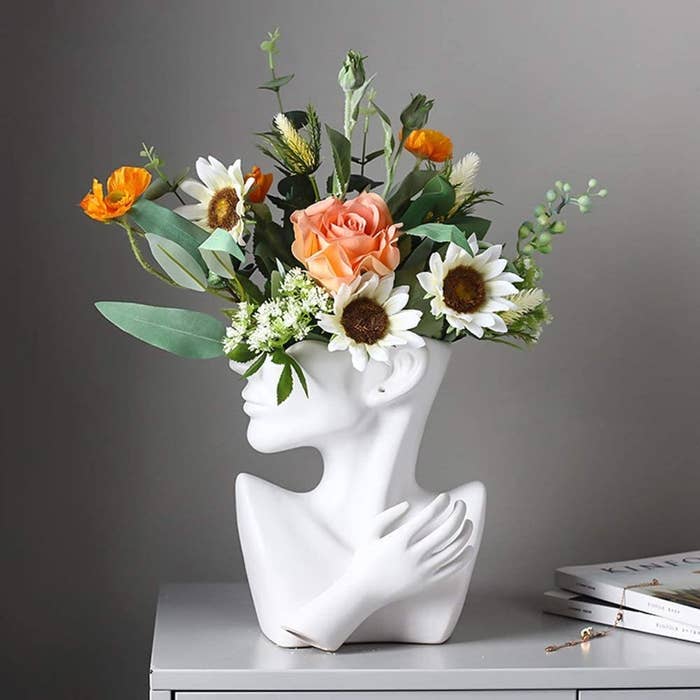a bust vase with flowers coming out of its head