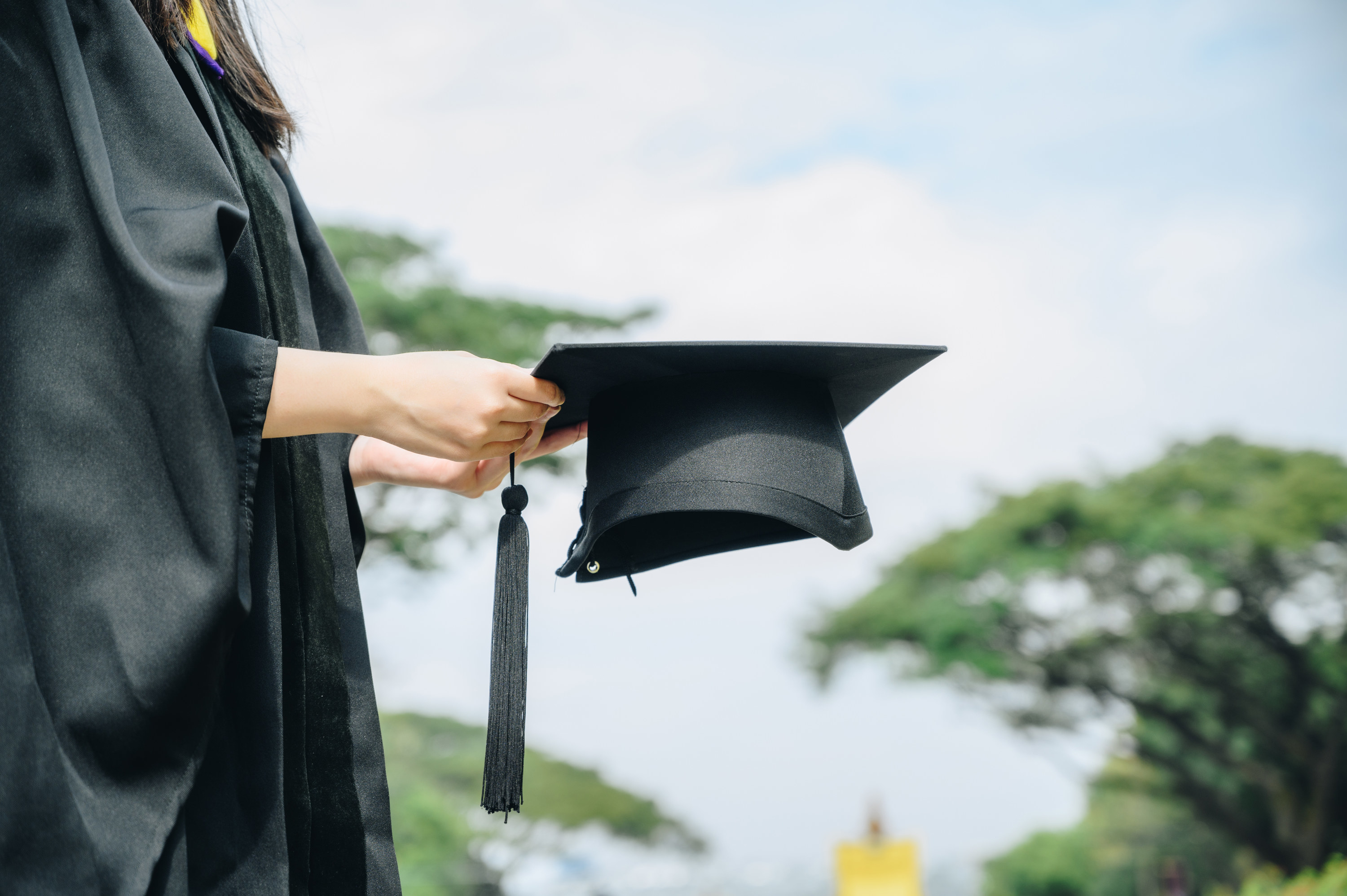 a person holding their cap while they graduate