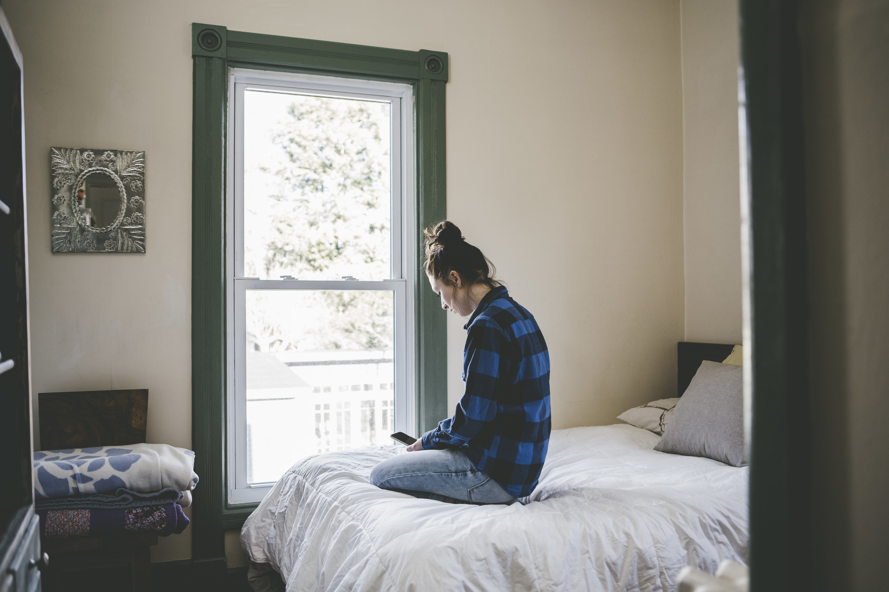 a person inside their home on their bed looking at their phone