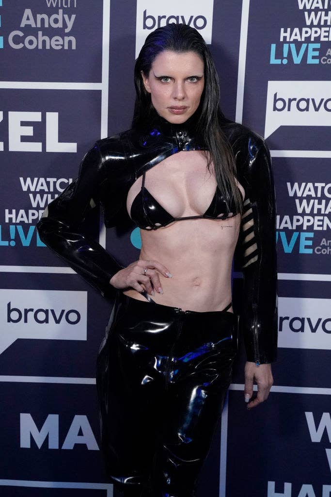 Julia poses on a red carpet with her hand on her hip. She&#x27;s wearing a leather bikini top and matching pants along with a matching bolero