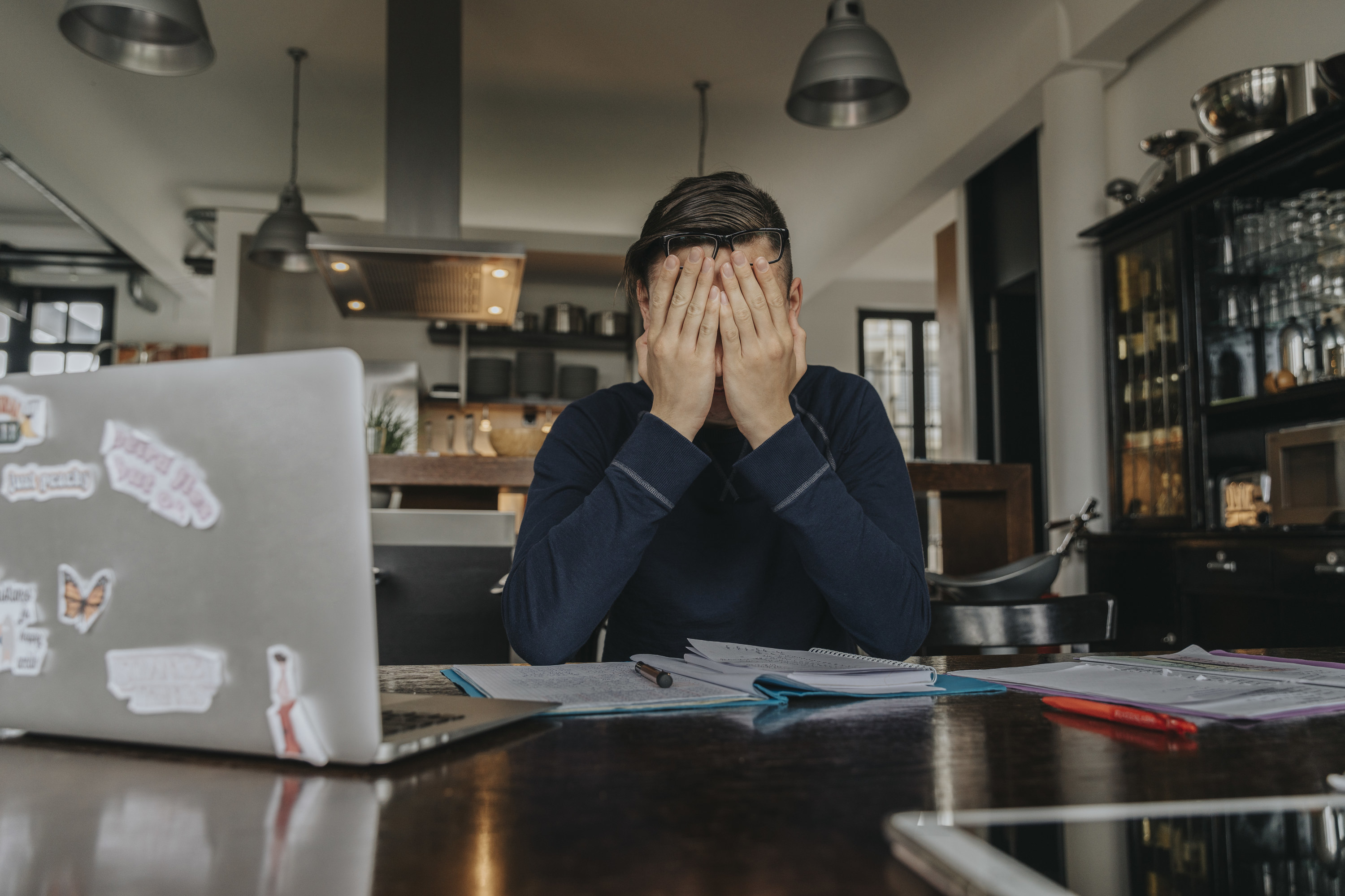 a man sitting at the table covering his face with his hands