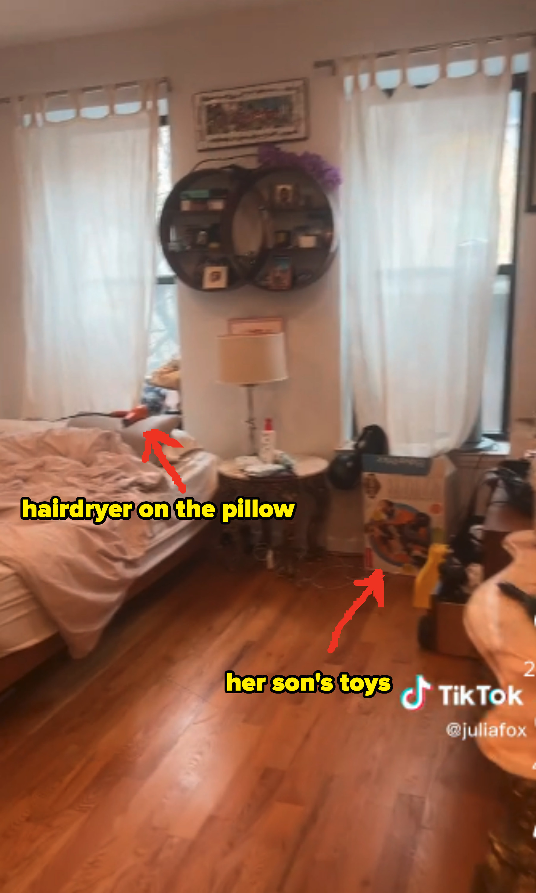 Julia&#x27;s unmade bed in on the left underneath one of the windows with a hairdryer lying on the pillow. Her son&#x27;s toys are also strewn about the room