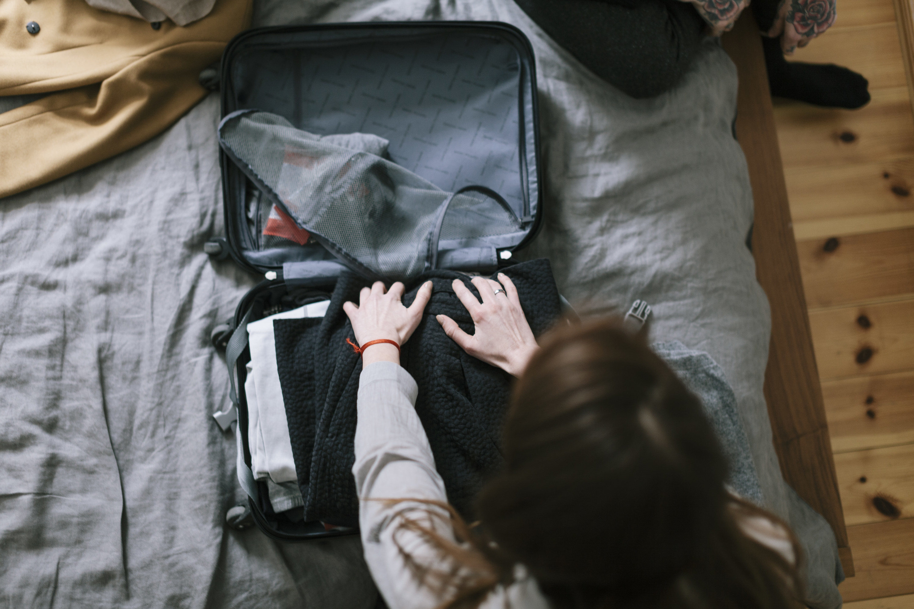 hands packing a suitcase on a bed