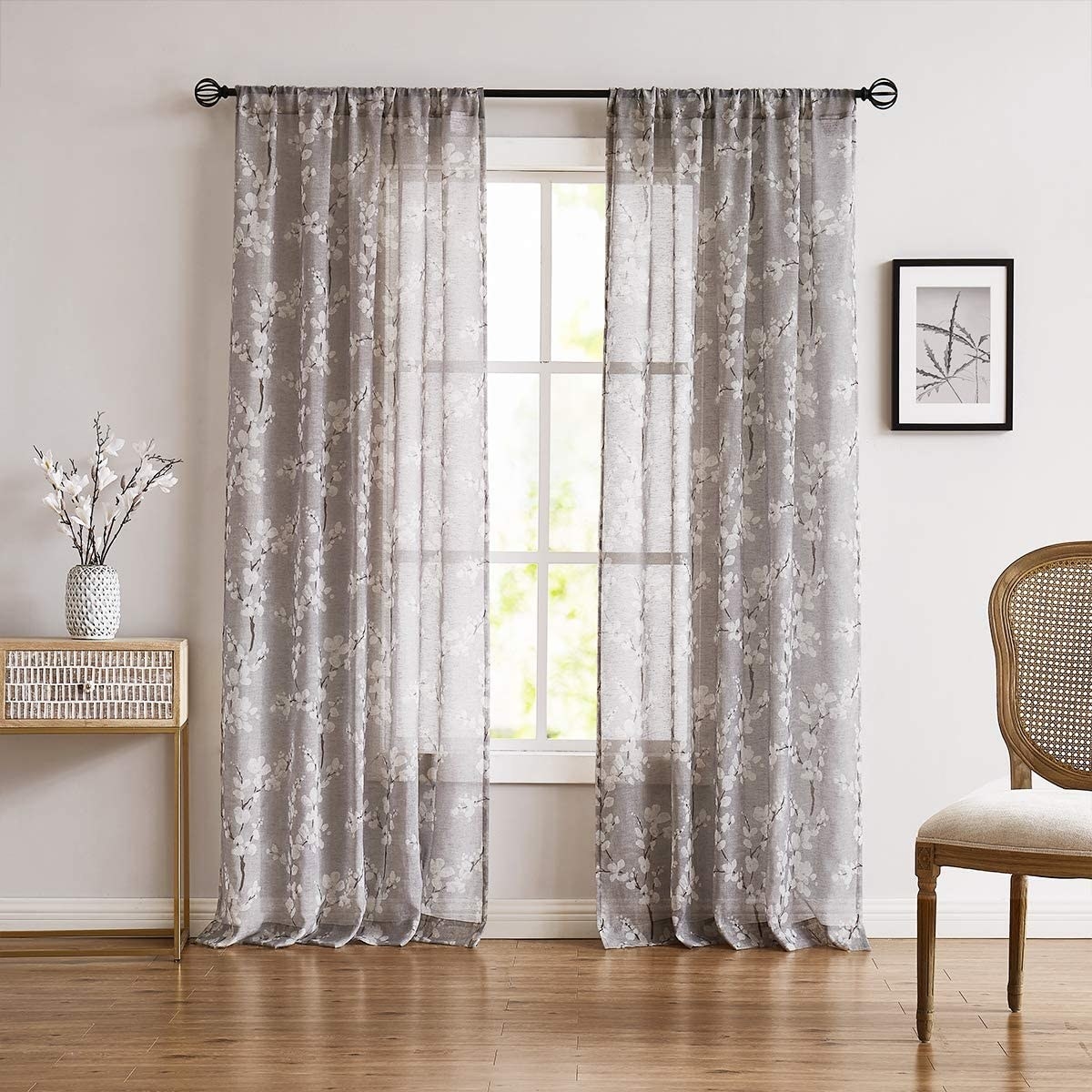 a pair of sheer, floral curtains on a large window