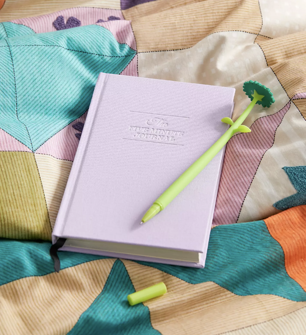 the journal with a floral pen on top of a bed