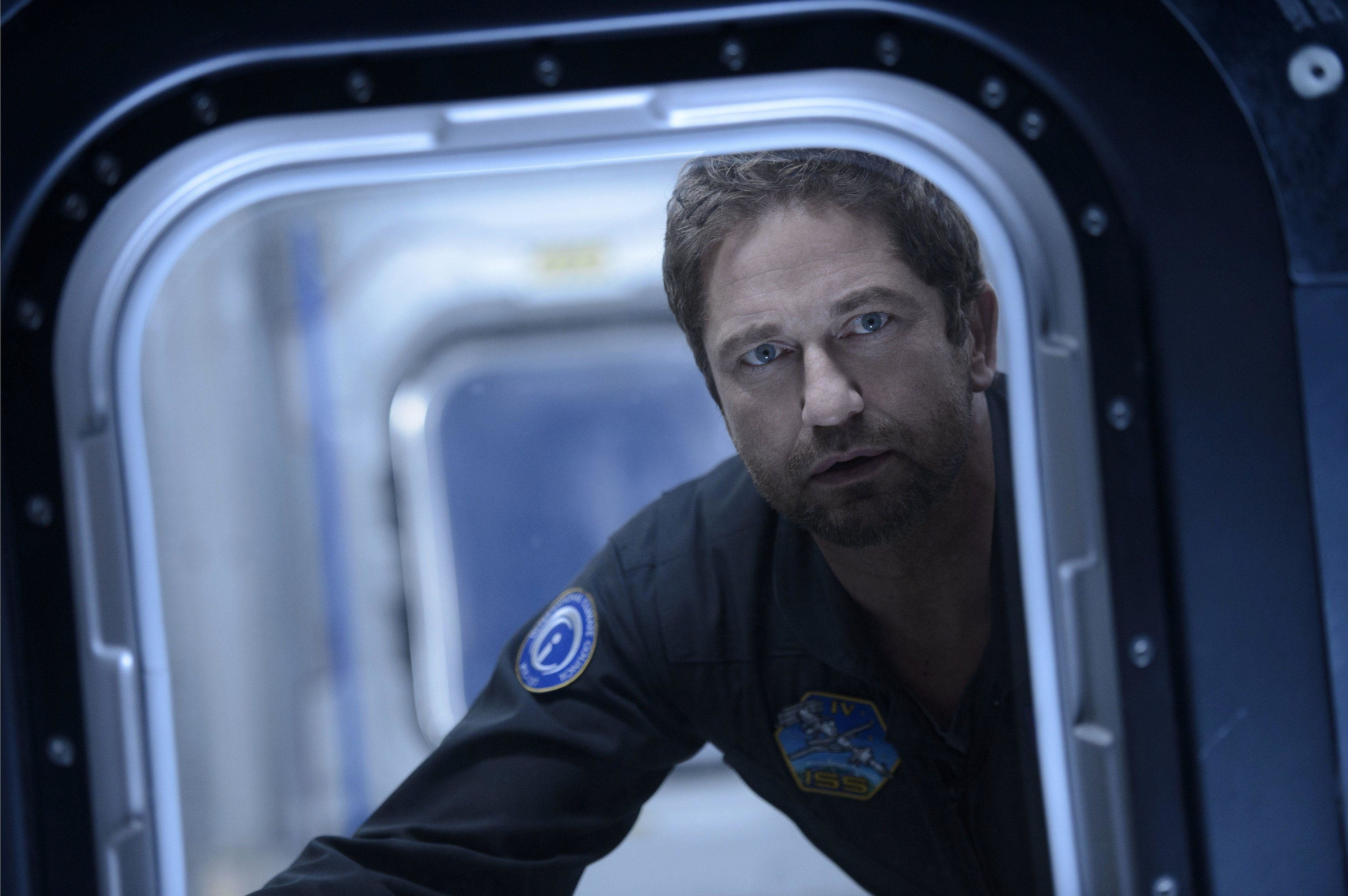 An astronaut looks out of a space vessel with concern