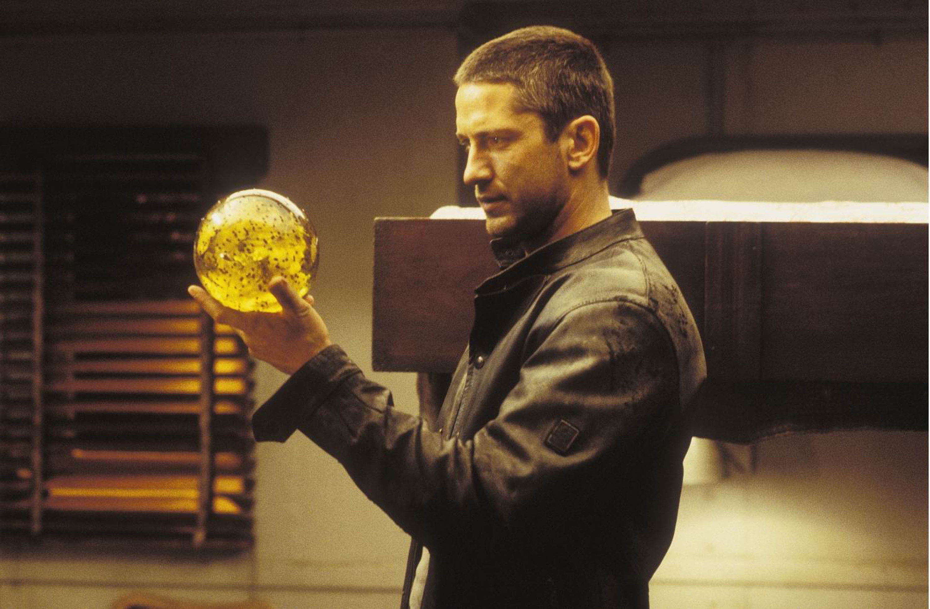 A short-haired man in a leather jacket holds a mysterious orb