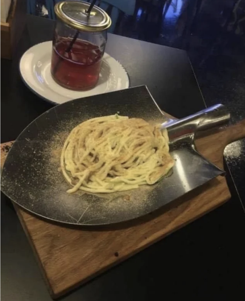Some pasta in what looks like a shovel on top of a cutting board