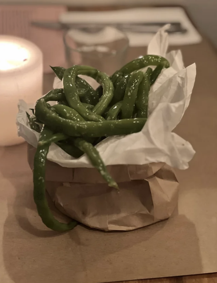 String beans jutting out of a brown paper bag