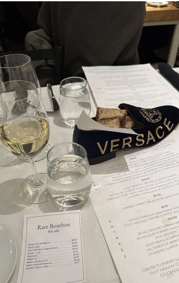 A bread basket in the shape of a shoe with &quot;Versace&quot; on it on a restaurant table