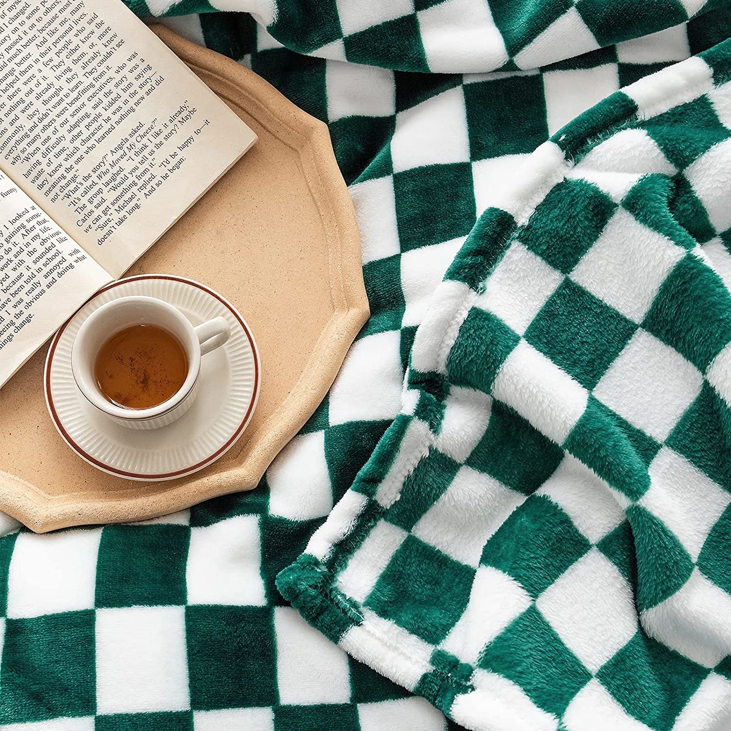 The blanket on a bed with a tray, a teacup, and a book on it