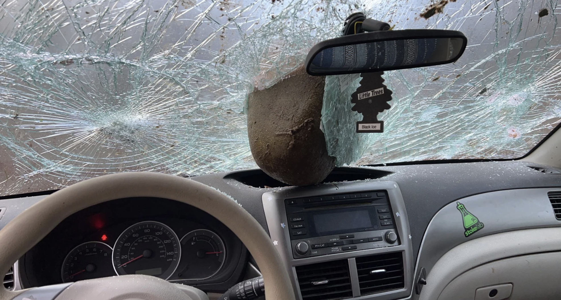 A photo from inside the car shows the rock crashed halfway through the windshield and into the interior