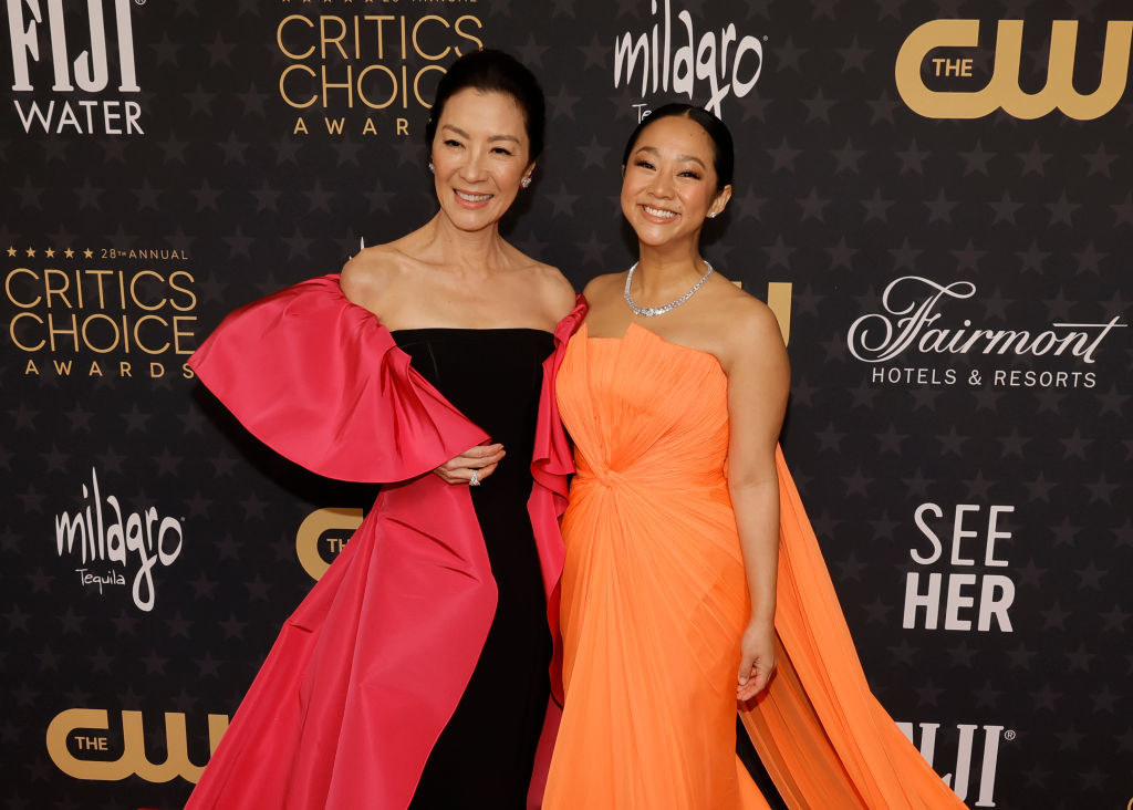 Michelle and Stephanie smile as they pose together on the red carpet of the Critics Choice Awards