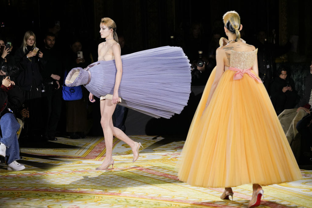 two models walking with dresses worn in abstract ways