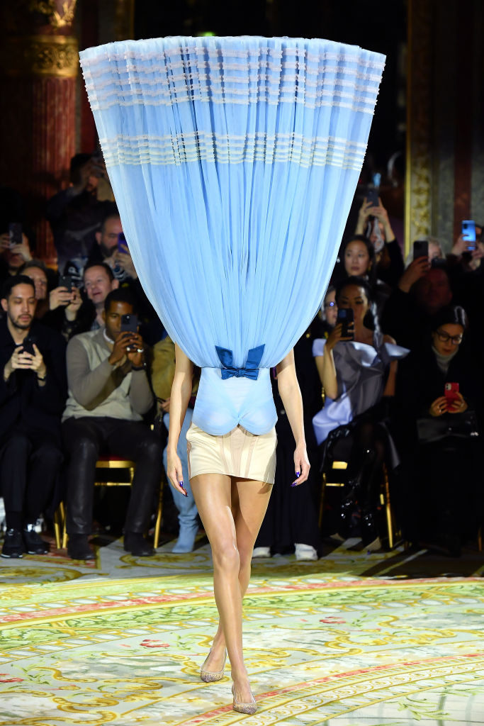 model walking with a dress attached upside down, covering her face