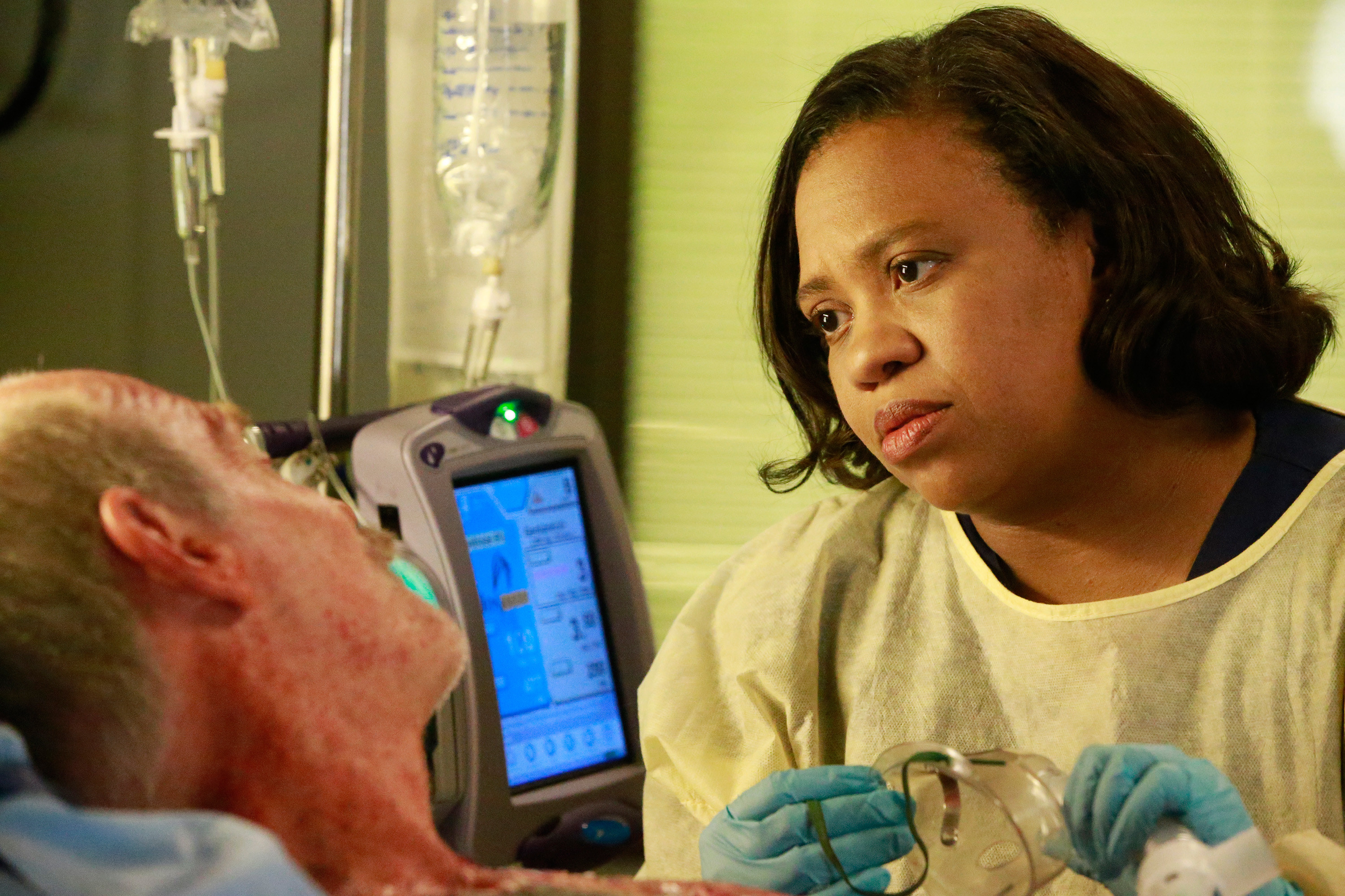 Chandra Wilson, in scrubs, looking at Casey Sander, who&#x27;s in a hospital bed in the episode &#x27;Things We Lost In the Fire&#x27;
