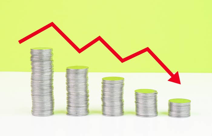 Descending stock market arrow over stacks of coins