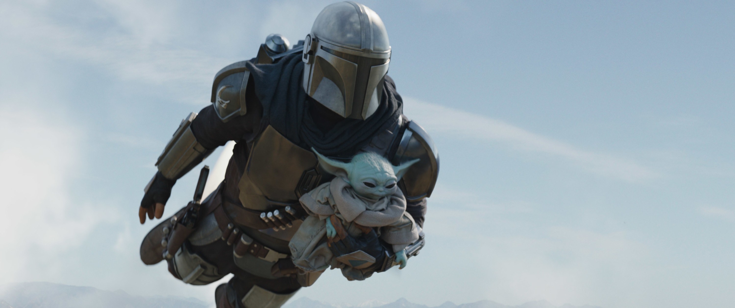 Mando holding Grogu while flying