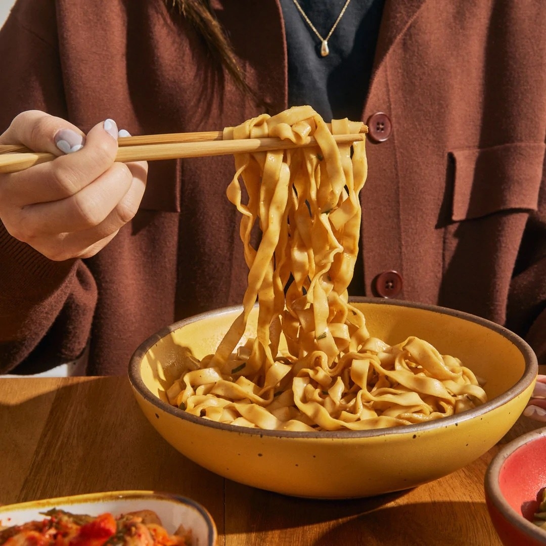 person eating noodles out of a bowl
