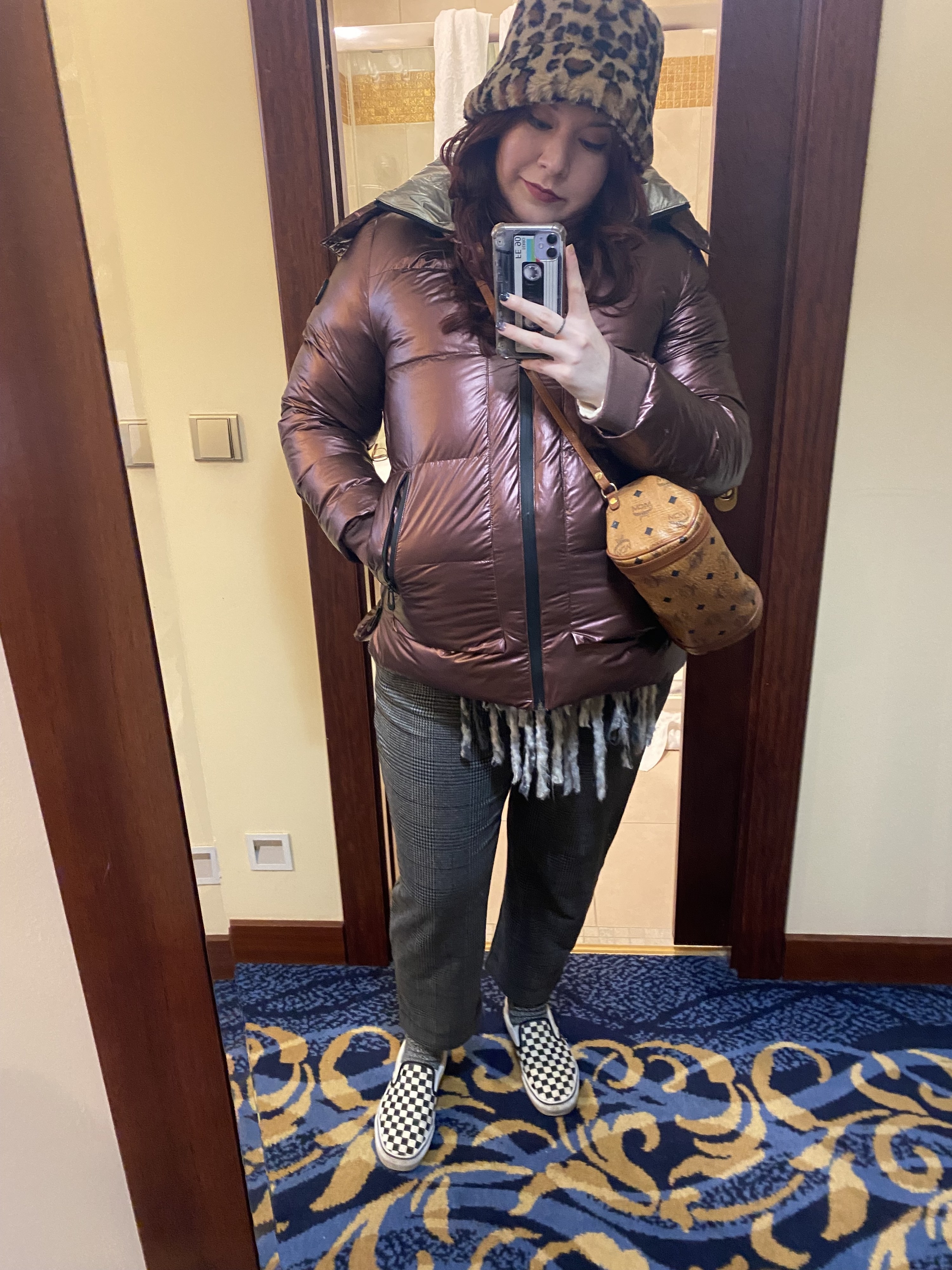 the writer wearing the pants in plaid with slip-on sneakers and a puffer coat