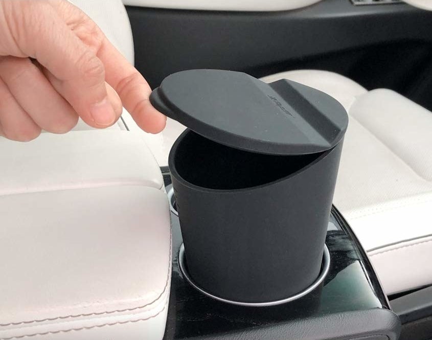 someone lifting the lid on the petite car trash can