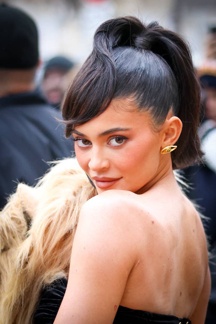 Kylie posing for a photo by looking over her shoulder while wearing a strapless Schiaparelli dress with a faux lion&#x27;s head attached to the front