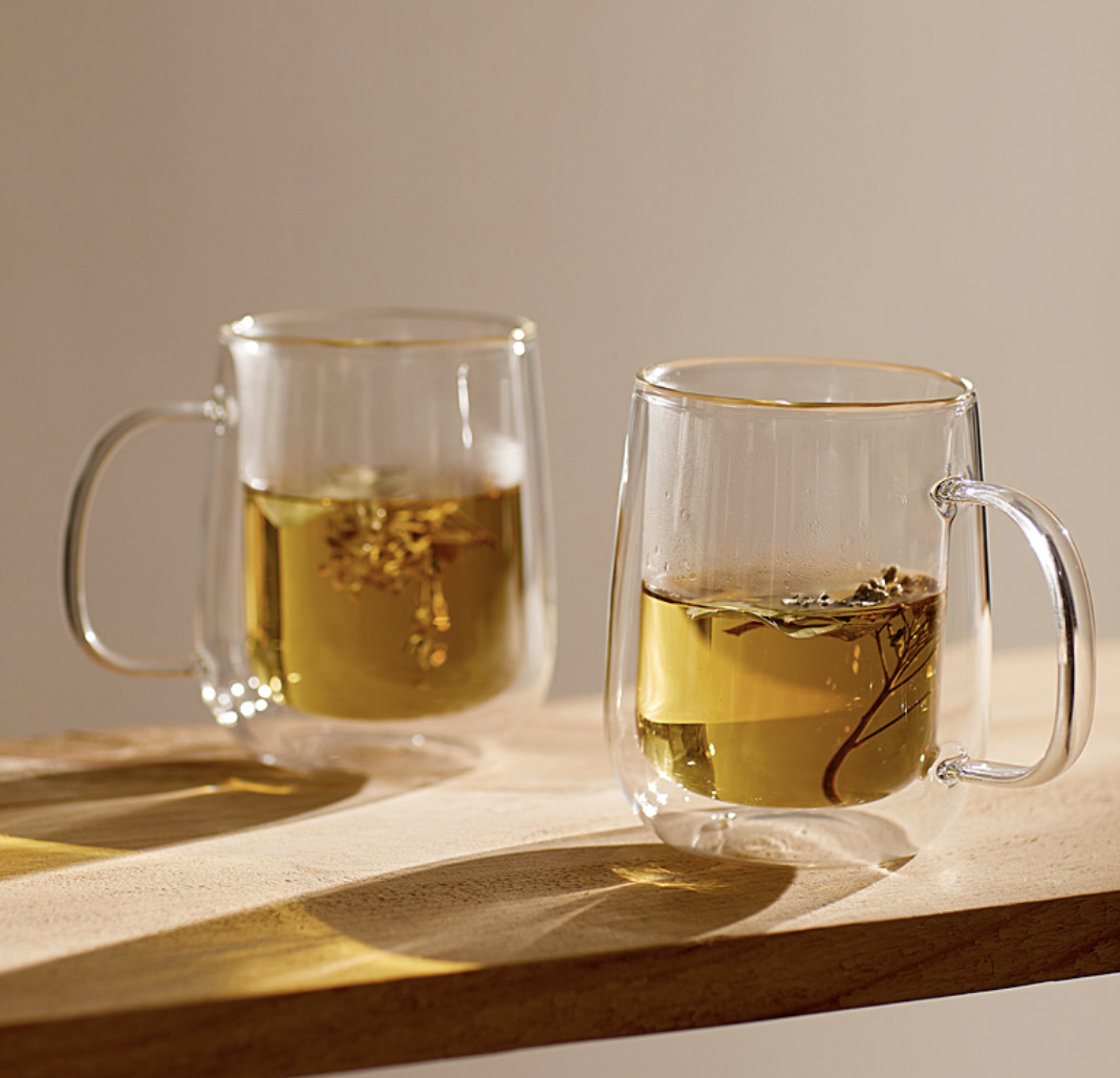 the pair of mugs with tea in them on a wooden plank