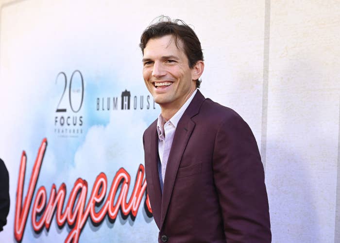 Ashton smiles widely as he walks the red carpet at an event