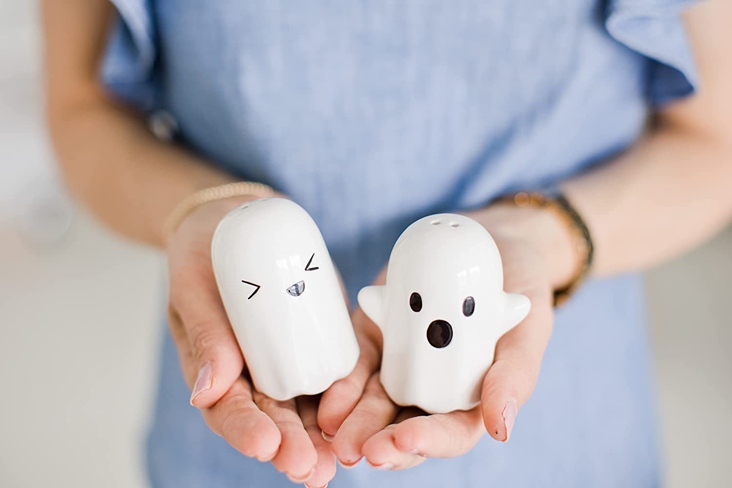 a person holding the ghost shaped salt and pepper set