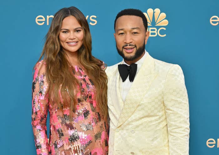 The couple smiling for photographers on the Emmys red carpet. Chrissy is wearing a sequined gown and John is wearing a tux with a large bowtie