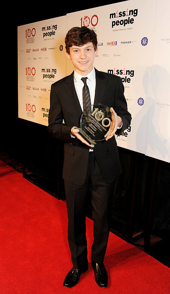 tom holding an award on the red carpet