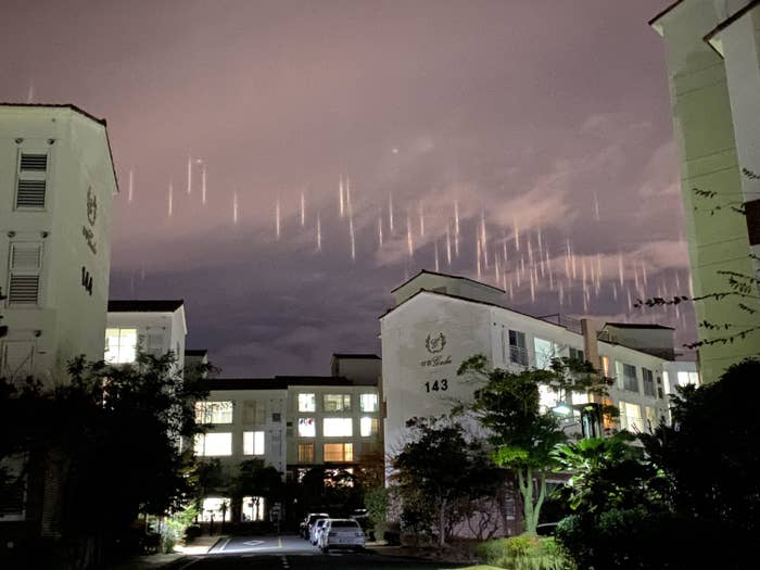 A bunch of short vertical lights in the sky above some apartment buildings