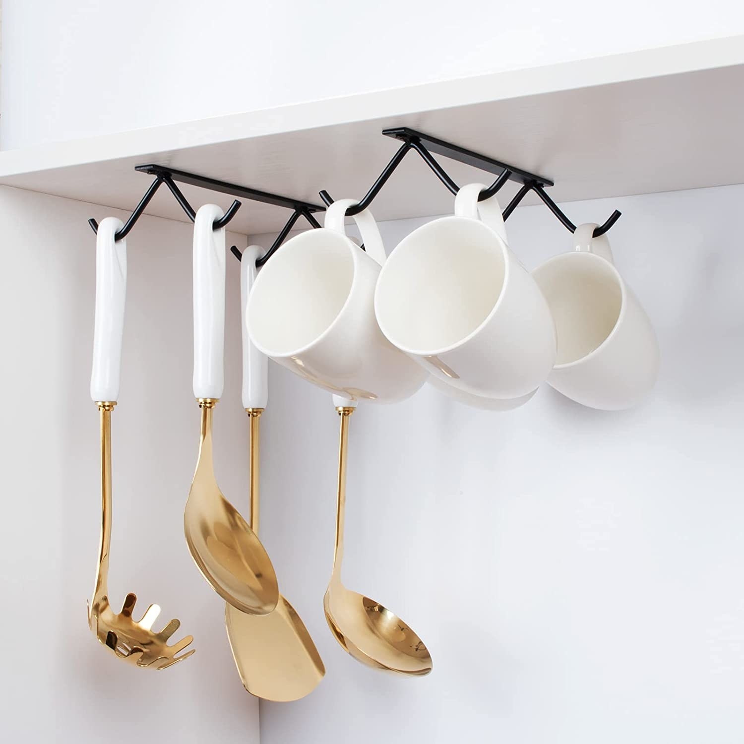 ladles and mugs hanging from the hooks which are mounted under a cabinet shelf