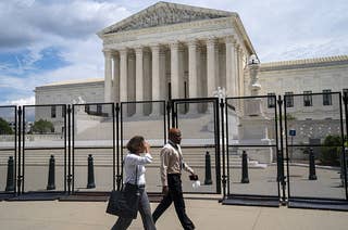 Two civilians walk past the fenced off United States Supreme Court building