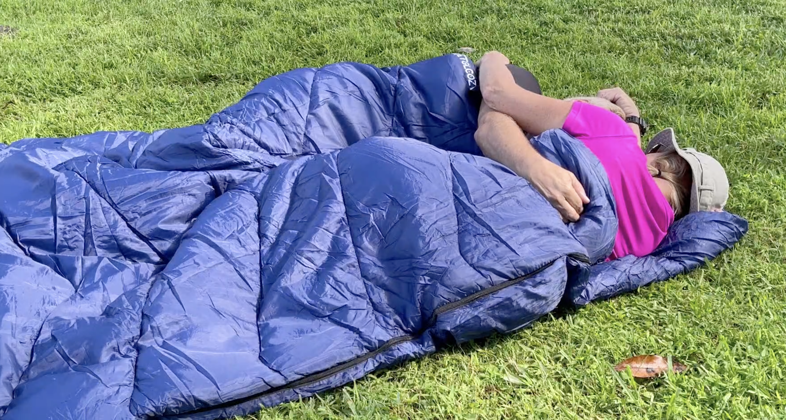 couple cuddling in the sleeping bag on the grass