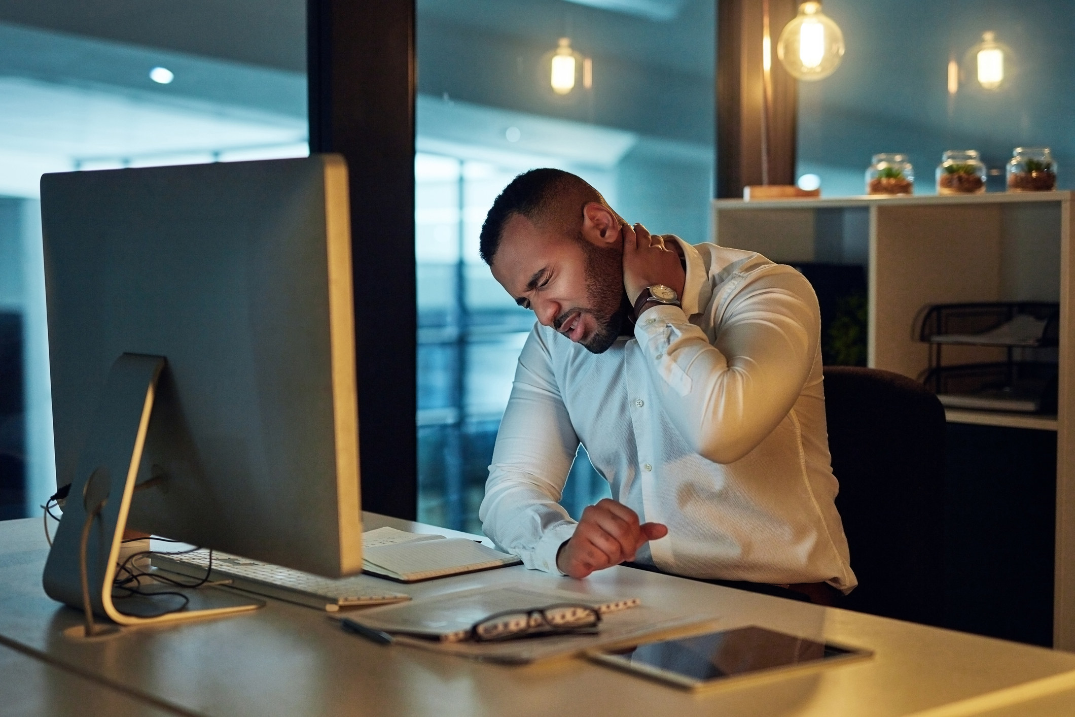 Someone holding on to neck in pain while at the computer