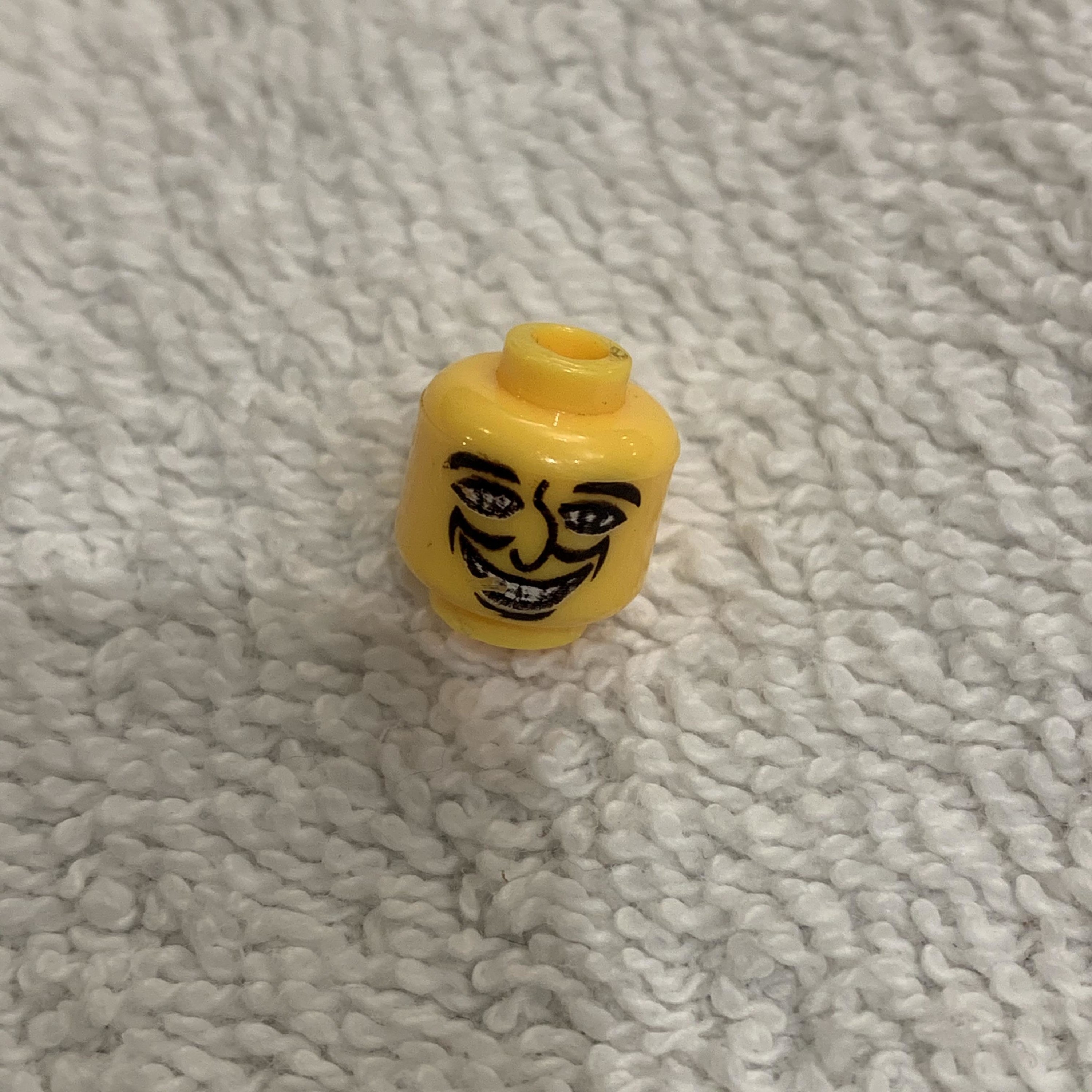 A lego person head that has a large grin and wide eyes