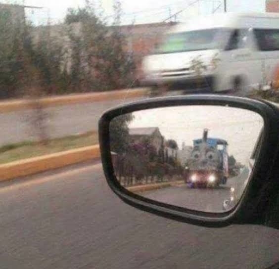 Thomas the Tank Engine driving up behind someone&#x27;s car, as seen from the side view mirror
